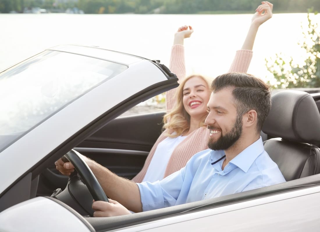 Personal Insurance - Happy Couple Smiling in a Convertible Car on a Road Trip